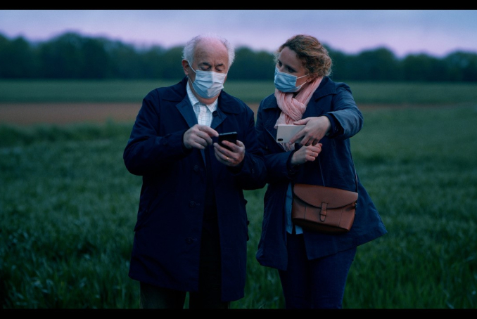 Photo représentant un homme âgé et une jeune femme qui l'aide à utiliser son téléphone portable 