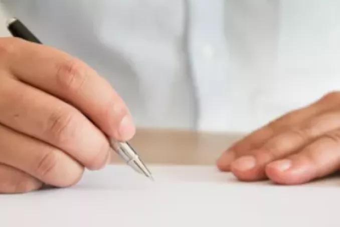 Mains posées sur la table, avec un stylo. Pas d'information sur le visuel.